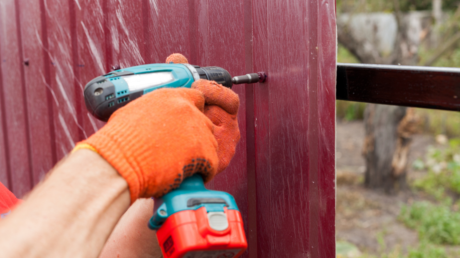 Drilling maroon-colored metal sheet for fence installation